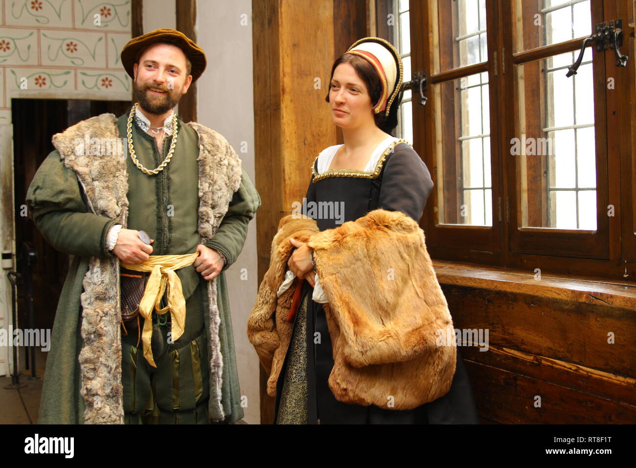 A well dressed Tudor couple chat in front of a large fireplace at The Tower of London Stock Photo