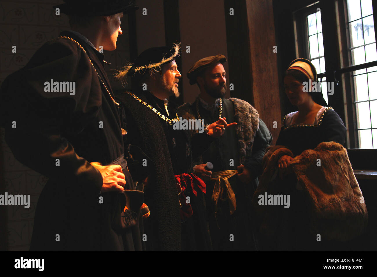 Henry VIII, his advisors and a Tudor woman chat inside The Tower of London- they are happy and wear authentic clothes Stock Photo