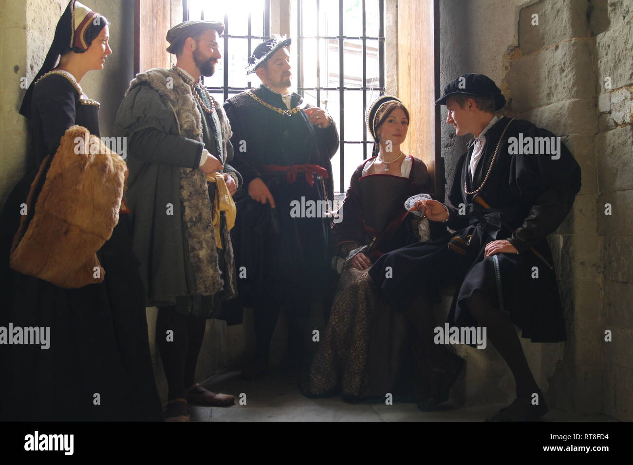 Henry VIII and Anne Boleyn with their advisors sit in a window seat at The Tower and have a conversation- they are dressed authentically Stock Photo