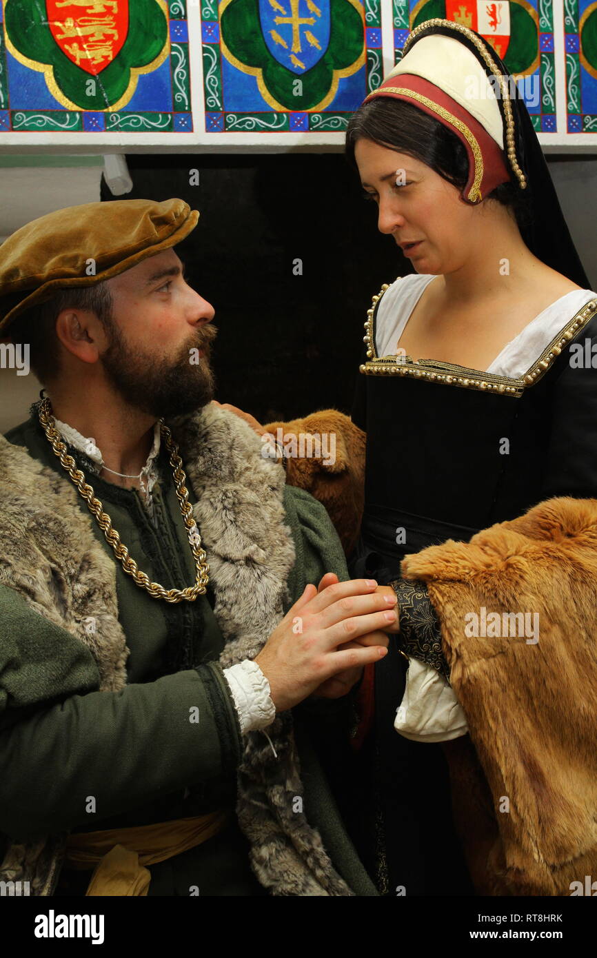 A well dressed Tudor couple chat in front of a large fireplace at The Tower of London Stock Photo