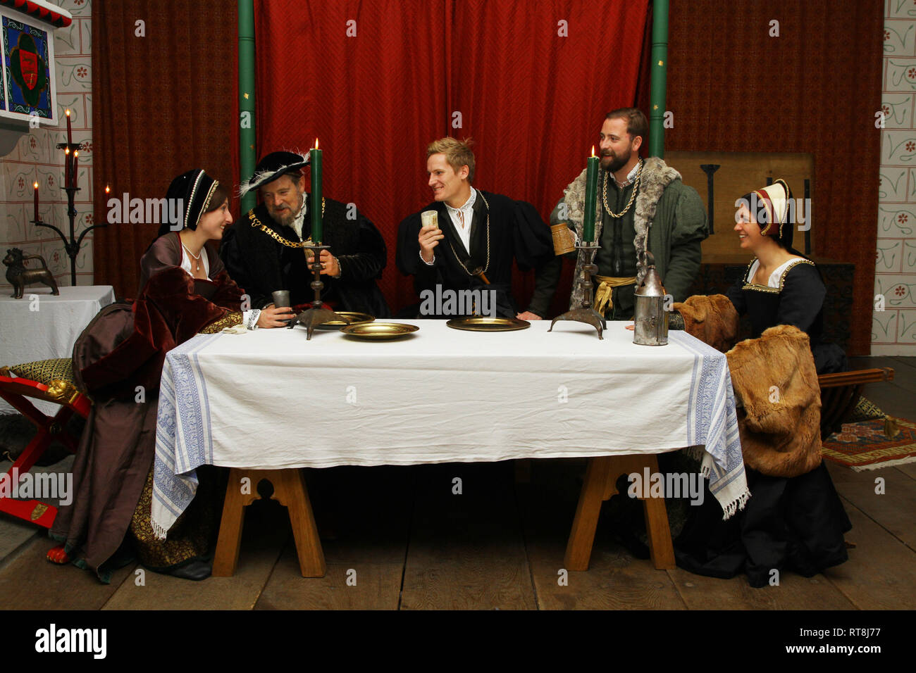 Five people dressed in accurate Tudor dress are having a banquet at The Tower of London. Henry VIII and Anne Boleyn and friends are there. Stock Photo