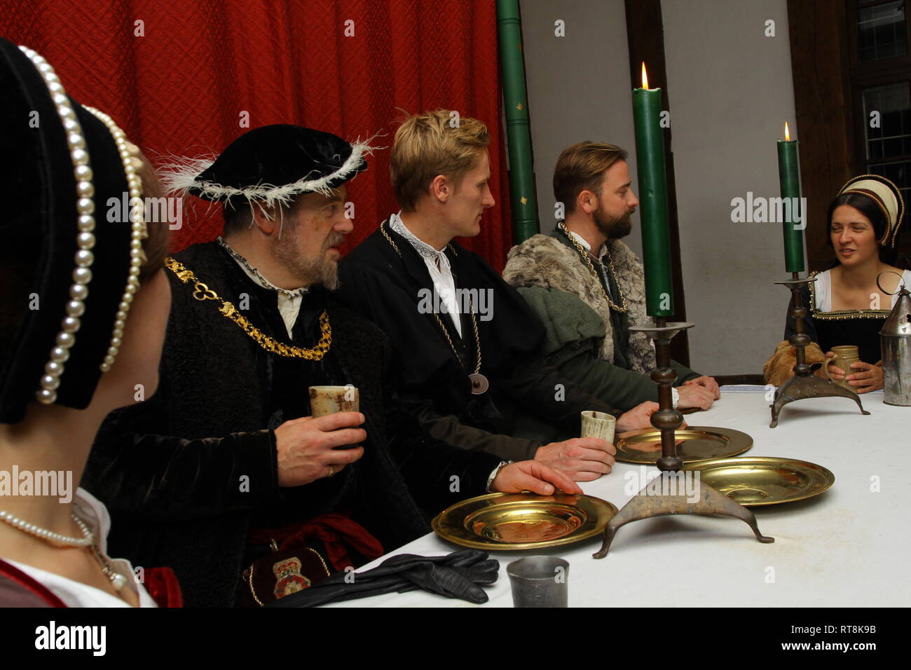 Five people dressed in accurate Tudor dress are having a banquet at The Tower of London. Henry VIII and Anne Boleyn and friends are there. Stock Photo