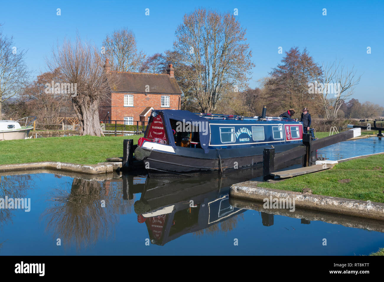 Papercourt Lock and lock keepers cottage on the picturesque River Wey Navigation in Surrey, UK, on a sunny day, with a narrowboat passing through Stock Photo