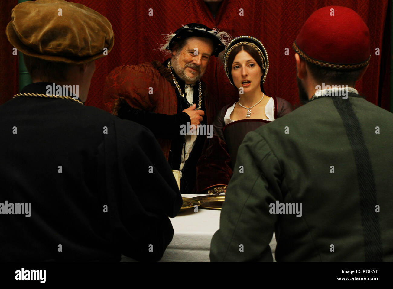 Henry VIII and Anne Boleyn are seated facing the camera- 2 men have their backs to it. they are having a meeting, their faces are animated Stock Photo