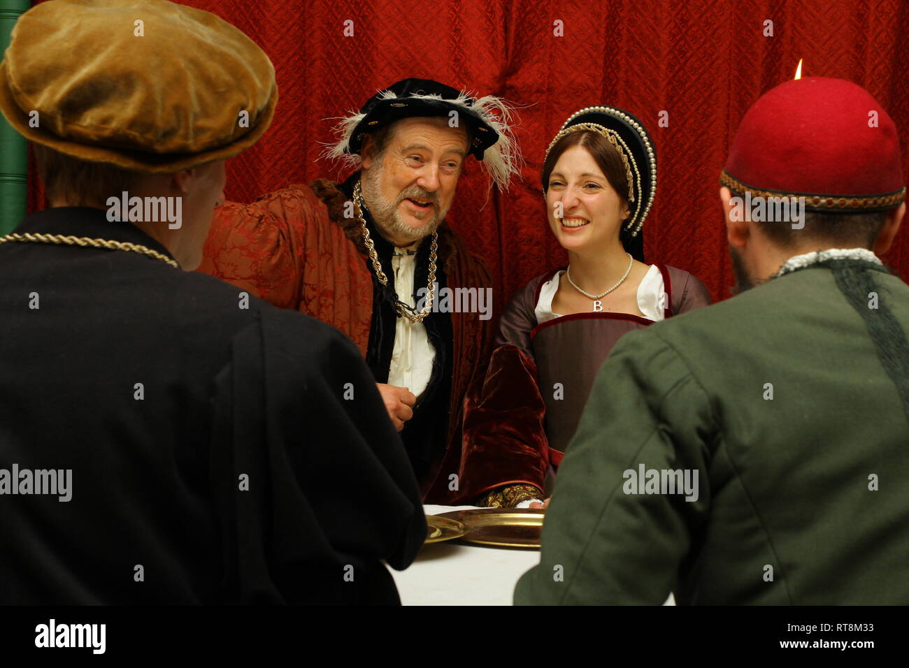Henry VIII and Anne Boleyn are seated facing the camera- 2 men have their backs to it. they are having a meeting, their faces are animated Stock Photo