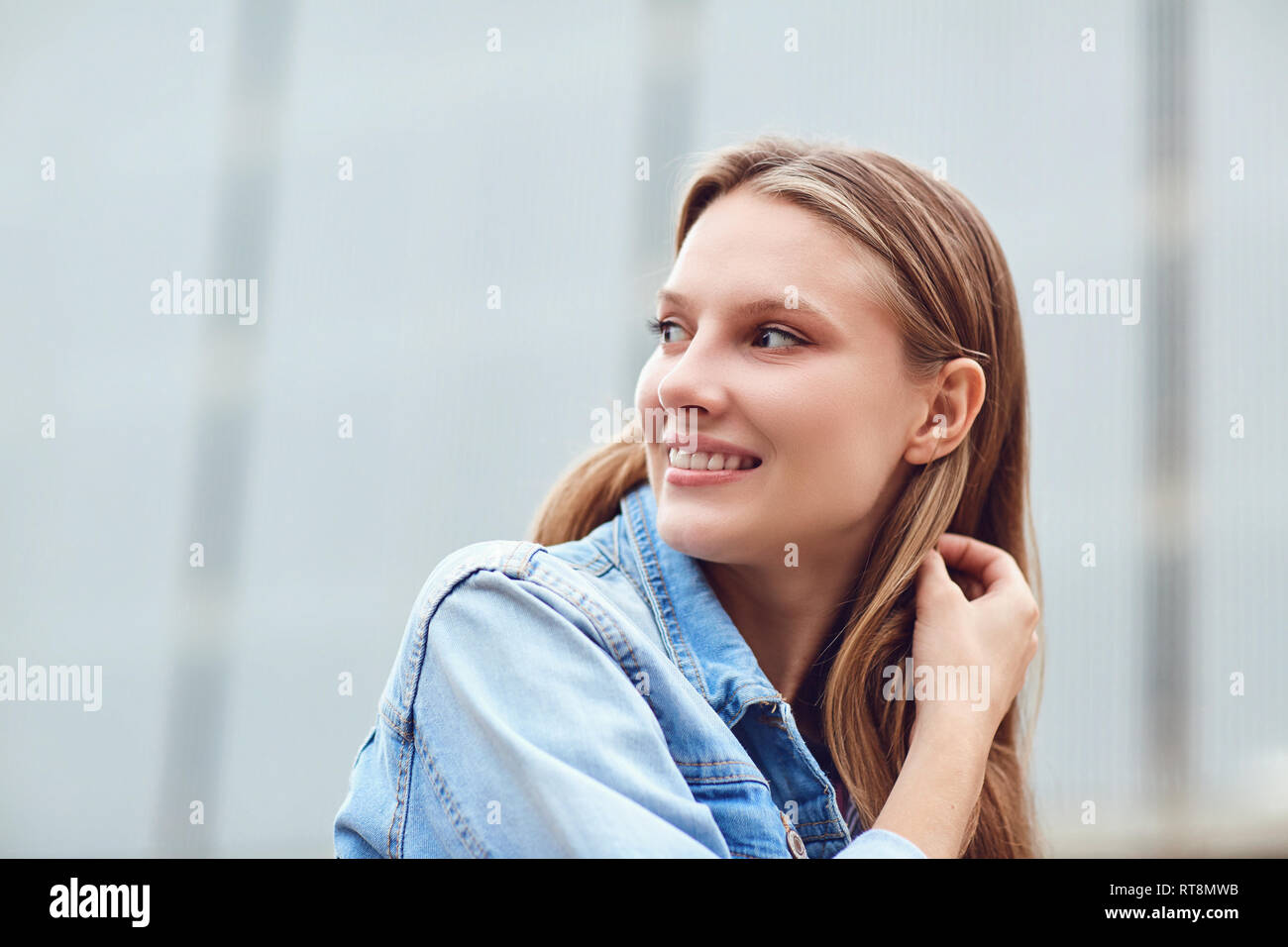 A blond happy girl smiles in an urban style.  Stock Photo
