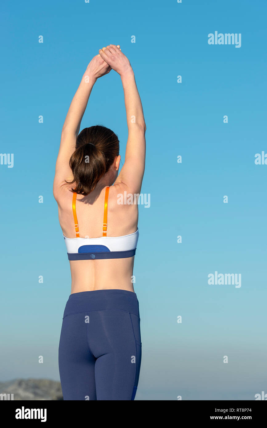 back view of a woman doing an arm stretch outdoors, morning warm up exercises Stock Photo
