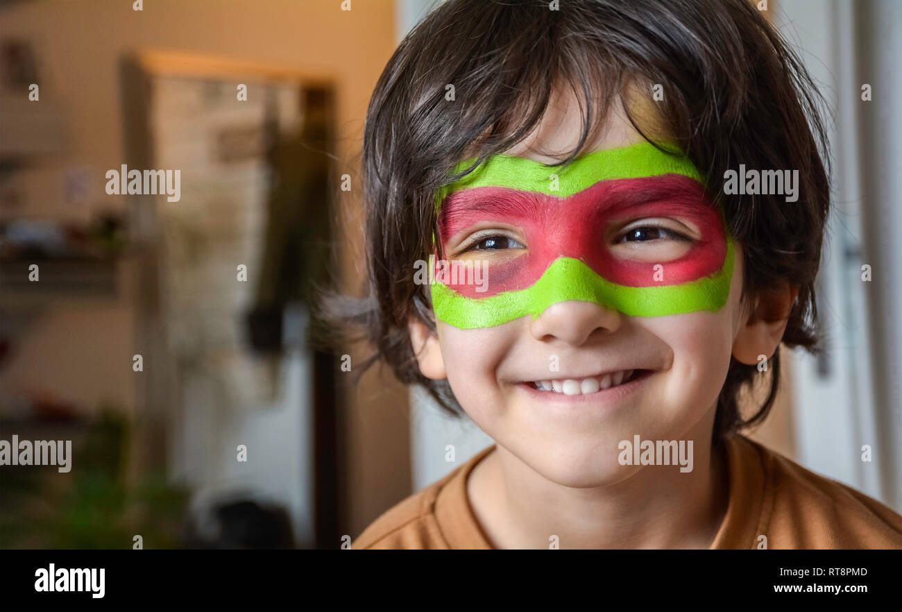Portrait of smiling boy with face painting - Painted child face on blurry background Stock Photo