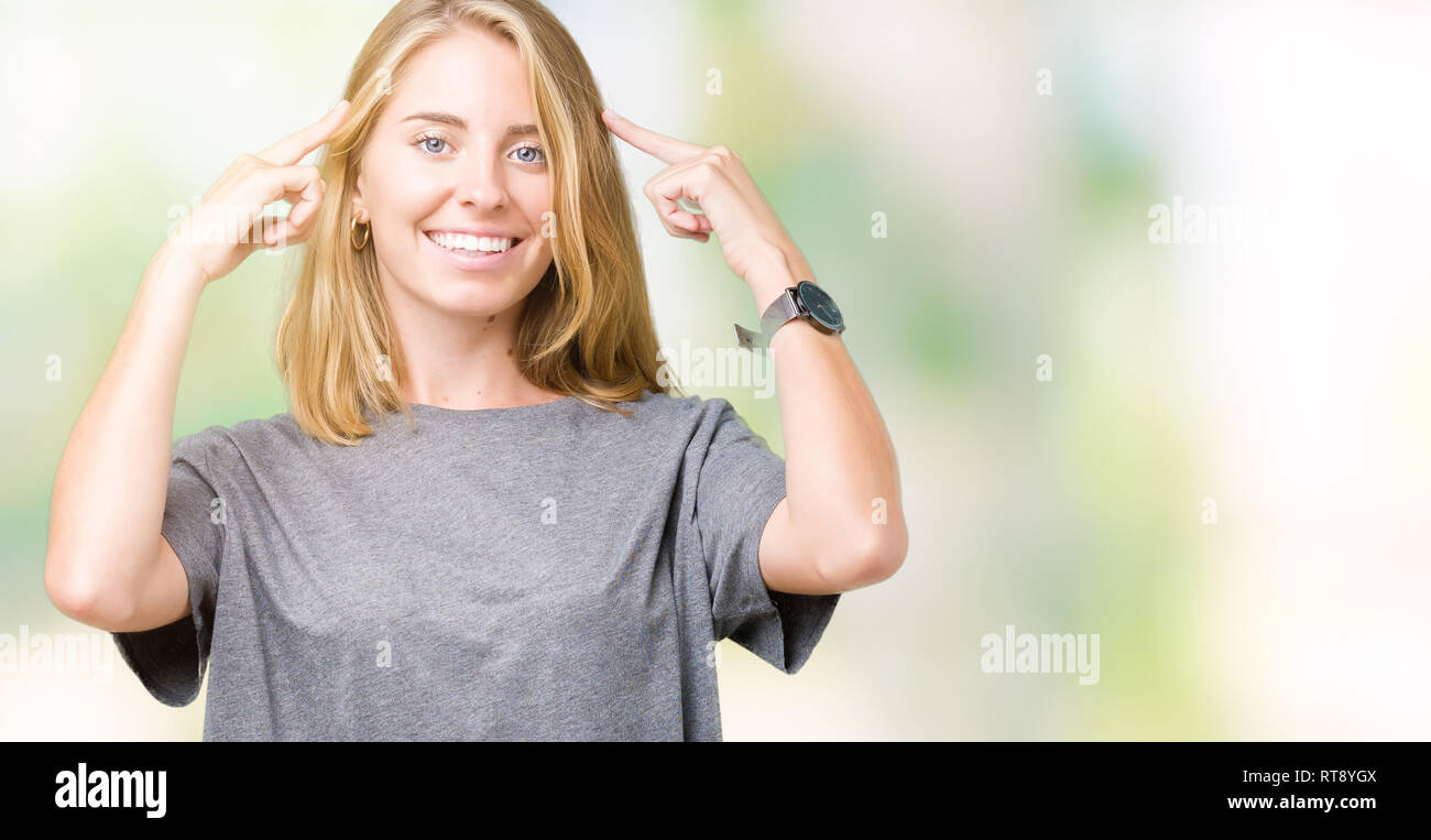 Beautiful young woman wearing oversize casual t-shirt over isolated background Smiling pointing to head with both hands finger, great idea or thought, Stock Photo