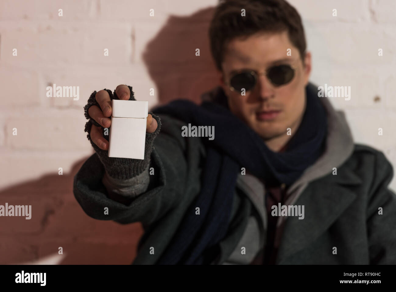 selective focus of homeless man in fingerless gloves and dark glasses ...