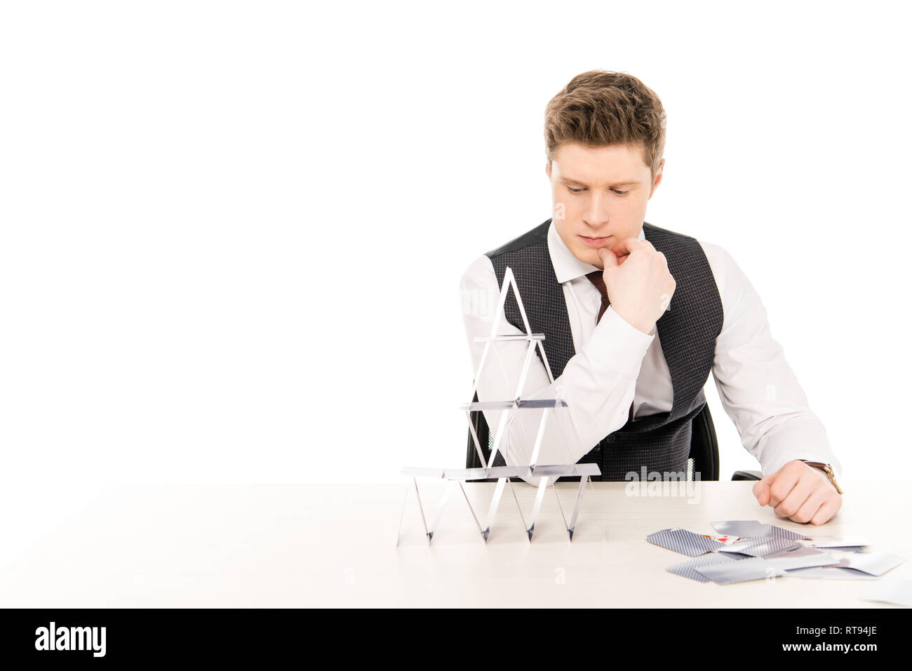 thoughtful male manager making pyramid from playing cards isolated on white Stock Photo