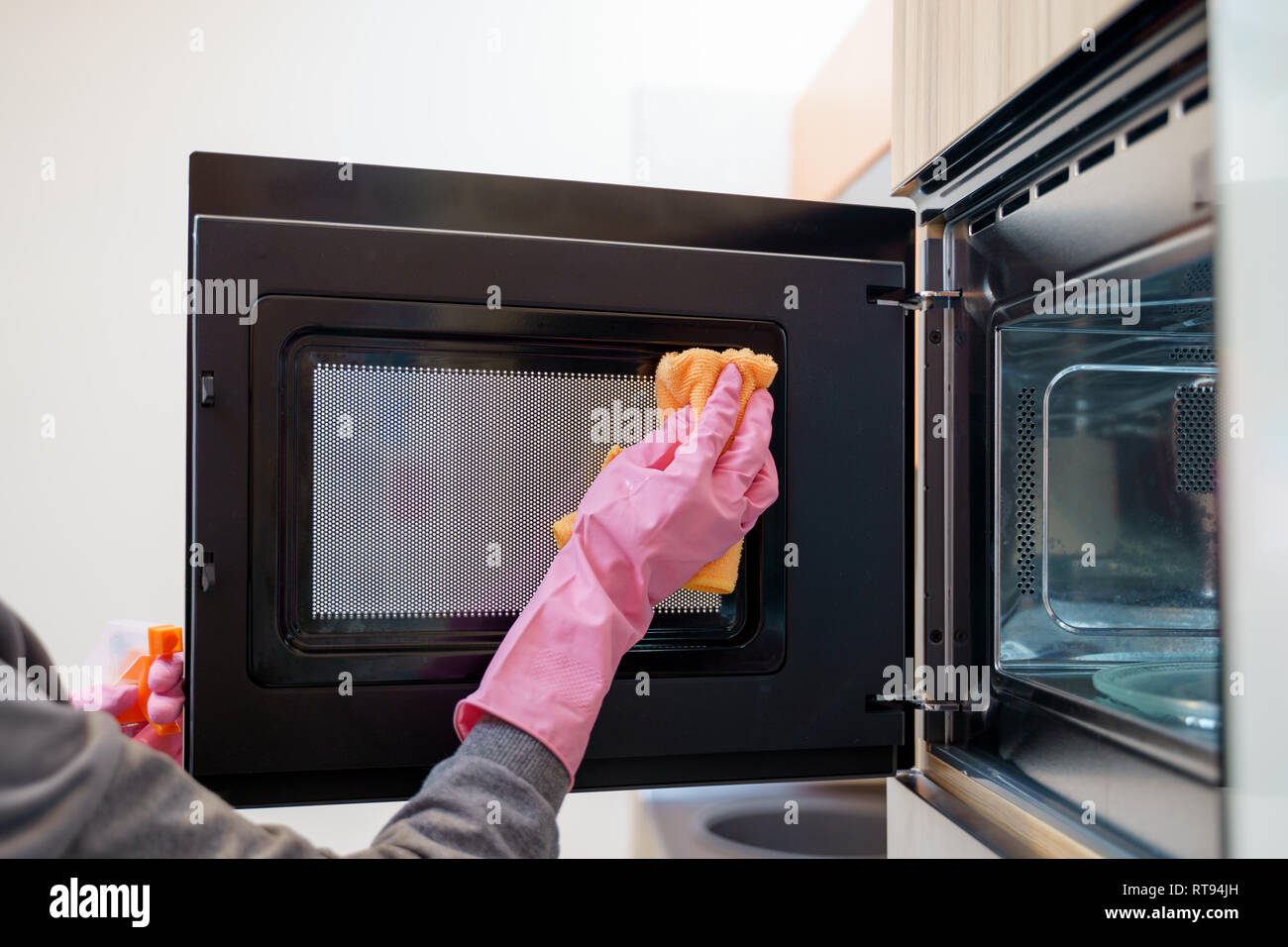 Photo of woman hands in rubber gloves washing microwave Stock Photo