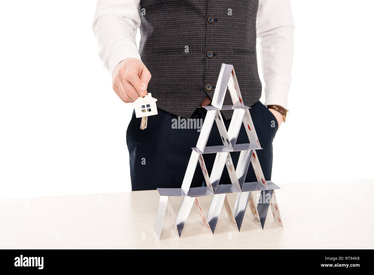 cropped view of realtor holding house keys and showing pyramid from playing cards, isolated on white Stock Photo