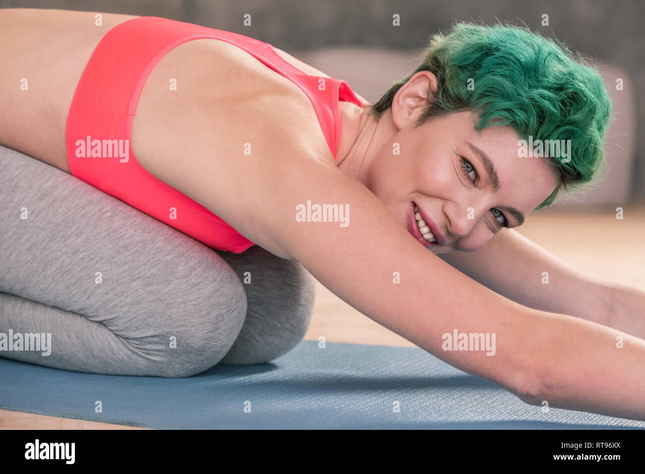 Appealing green-eyed woman smiling while stretching after gym Stock Photo