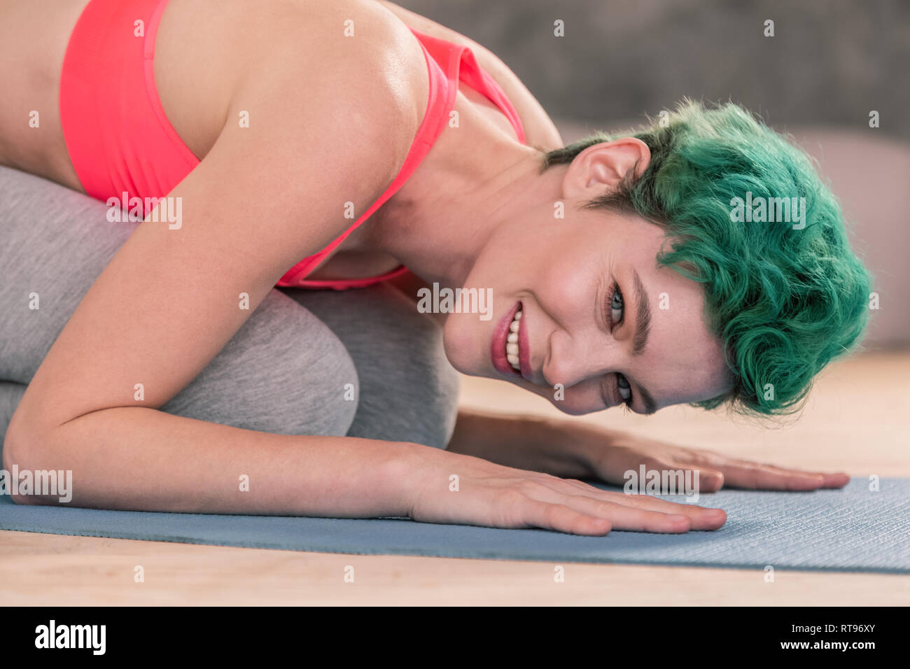 Green-haired woman wearing pink top working out on sport mat Stock Photo