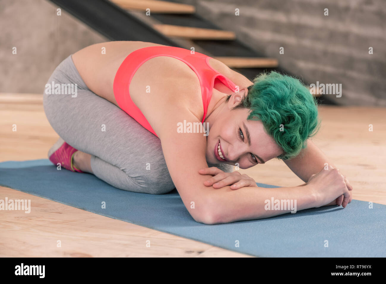 Green-haired woman doing yoga for beginners in the morning Stock Photo