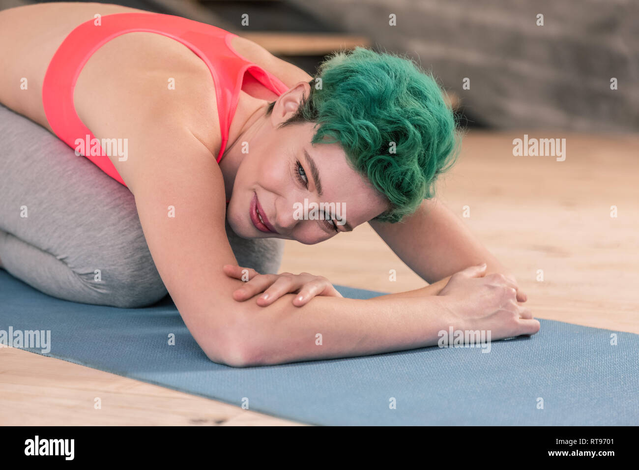 Green-haired woman wearing sport clothes stretching after fitness Stock Photo