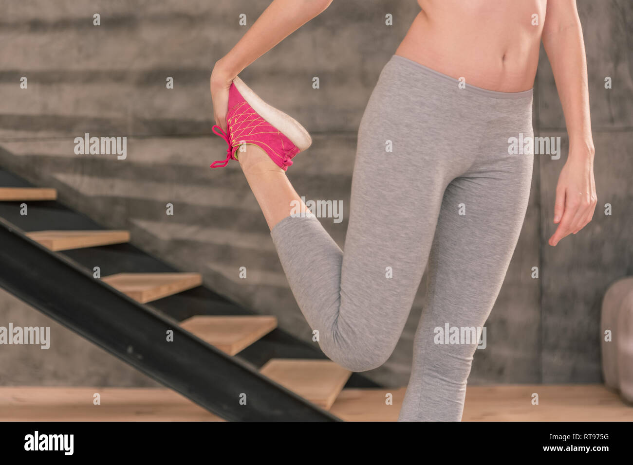 Slim woman wearing grey leggings stretching her legs after fitness Stock Photo