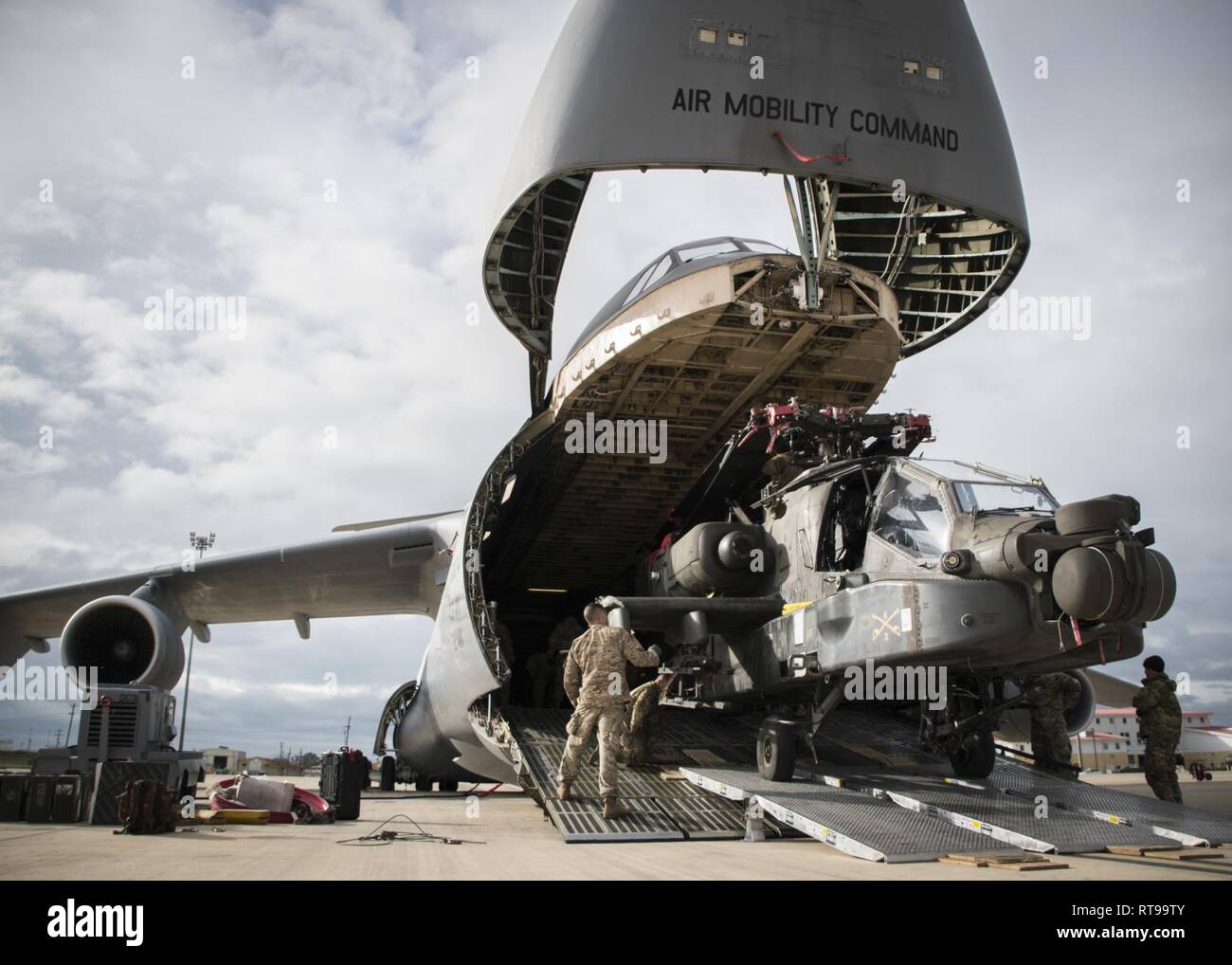 NAVAL STATION ROTA, Spain (January 30, 2019) Soldiers assigned to the 1st Armored Division and 1109th Theater Aviation Sustainment Maintenance Group load an AH-60 Apache helicopter onto a C-5 aircraft during Intermodal operations. Intermodal operations combine sea and air transportation to reduce cargo handling, improve security, minimize damage and allow quicker transportation. Stock Photo