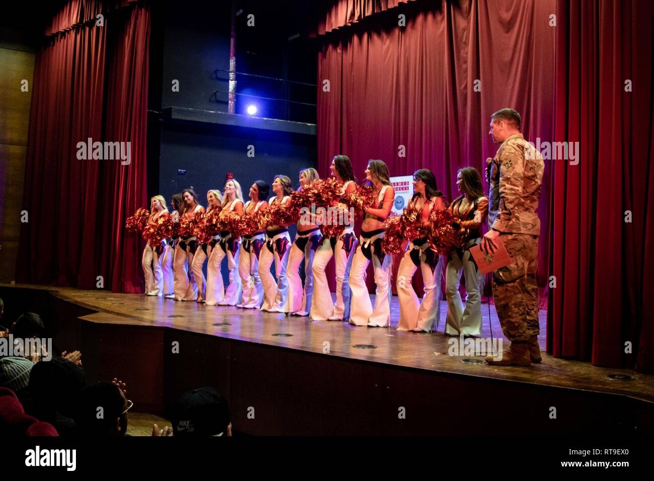 Col. Scott Galloway, the commander of the 4th Combat Aviation Brigade, 4th Infantry Division, thanks and presents a plaque to the Denver Broncos Cheerleaders at the close of their performance as part of the Denver Broncos Pro Blitz Tour, sponsored by Armed Forces Entertainment, at the theater in Illesheim, Germany, Jan. 28, 2019.    The Denver Broncos Pro Blitz Tour featuring the Denver Broncos Cheerleaders, Miles the team mascot and former players, is orchestrated by Armed Forces Entertainment in order to provide the best unique entertainment to U.S. troops and family members stationed overse Stock Photo