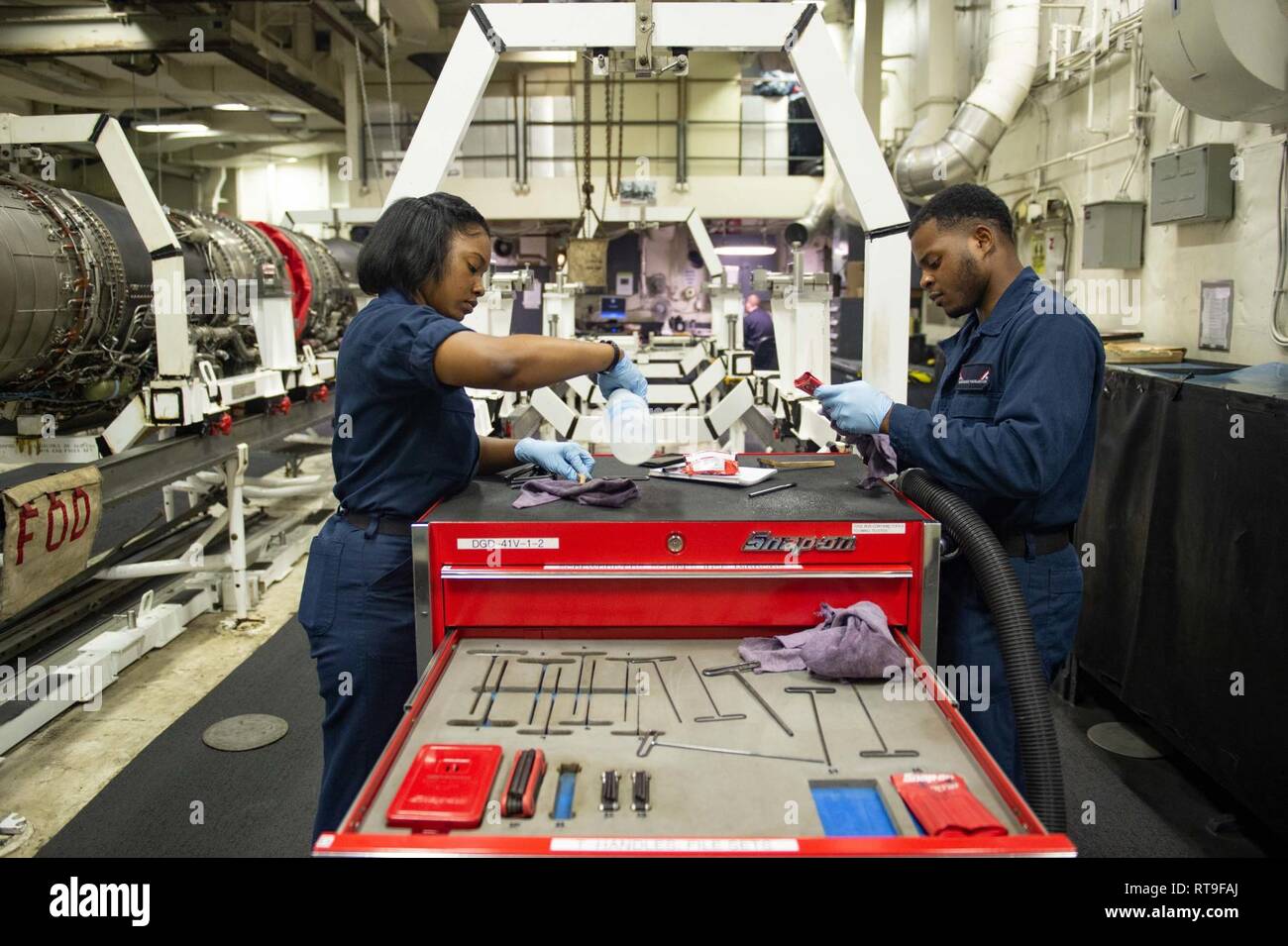 U.S. Navy Aviation Machinist’s Mate 3rd Class Yanique Johnson, left, from Fort Lauderdale, Florida, and Aviation Machinist’s Mate Airman Quintavious Haugadook, from Atlanta, clean tools in the jet shop aboard the aircraft carrier USS John C. Stennis (CVN 74) in the Indian Ocean, Jan. 29, 2019. The John C. Stennis is deployed to the U.S. 7th Fleet area of operations in support of security and stability in the Indo-Pacific region. Stock Photo