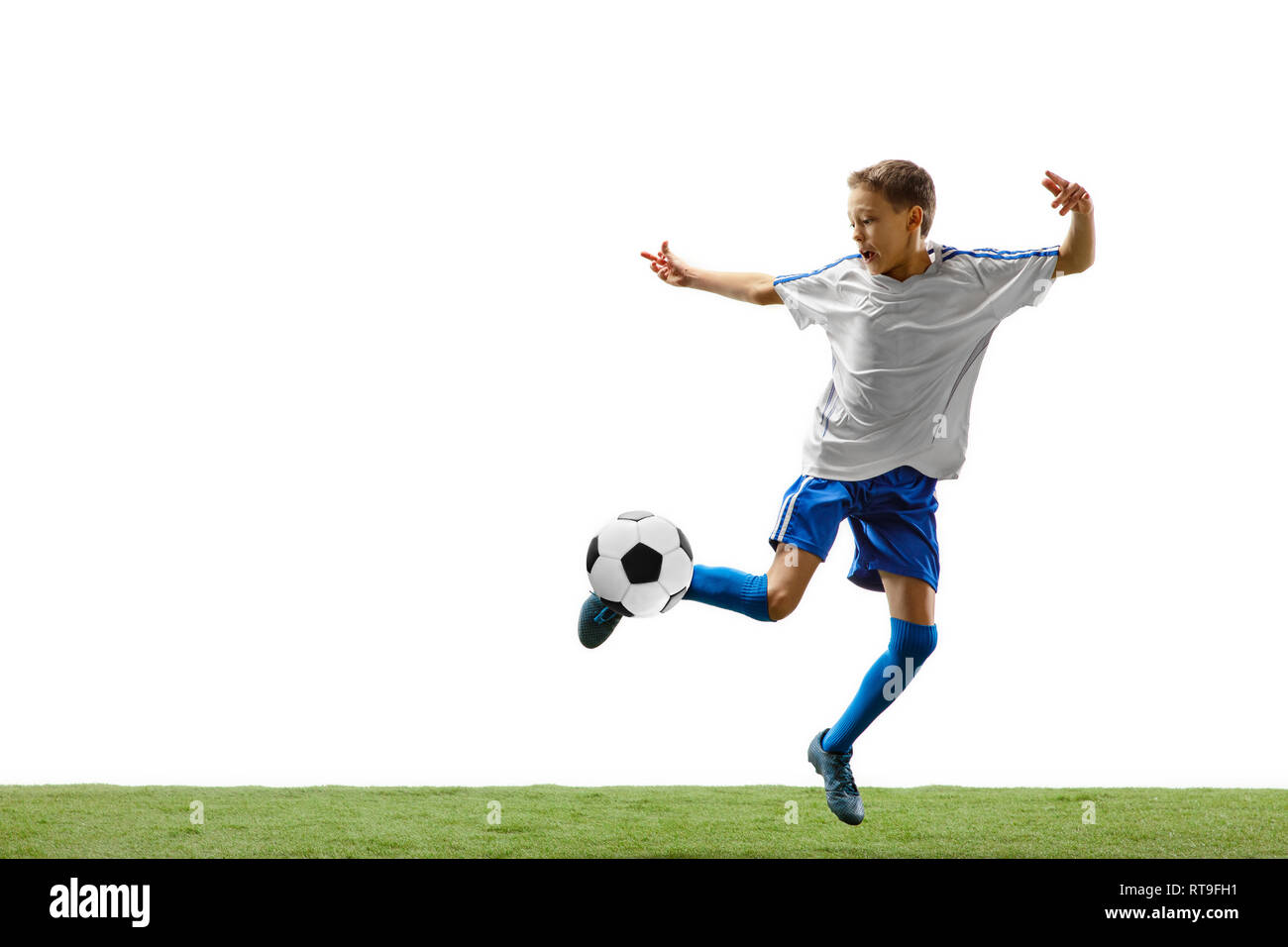 Young boy with soccer ball running and jumping isolated on white