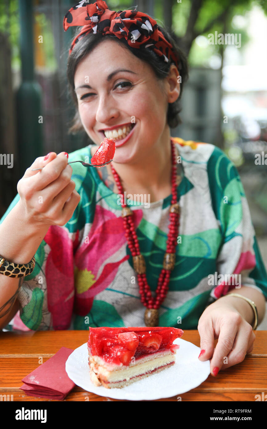 Woman eating strawberry cake in street cafe Stock Photo