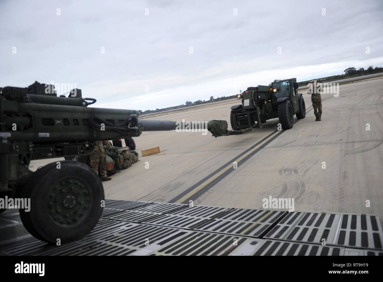 NAVAL STATION ROTA, Spain (Jan. 29, 2019) Seabees assigned to Naval Mobile Construction Battalion (NMCB) 1 and U.S. Air Force (USAF) airmen assigned to the 22nd Airlift Squadron download a U.S. Army M777 howitzer from a USAF C5M Super Galaxy during an embarkation operation. NMCB-1 is forward deployed to execute construction, humanitarian and foreign assistance, and theater security cooperation in the U.S. 6th Fleet area of operations. Stock Photo