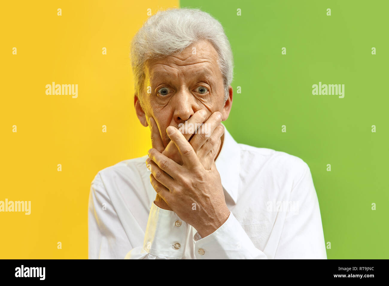 Serious senior frightened male keeps fingers on lips, tries to keep conspiracy, says: Shh, make silence please. Isolated shot of man shows silence gesture Stock Photo