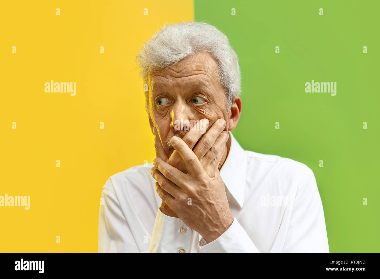 Serious senior frightened male keeps fingers on lips, tries to keep conspiracy, says: Shh, make silence please. Isolated shot of man shows silence gesture Stock Photo