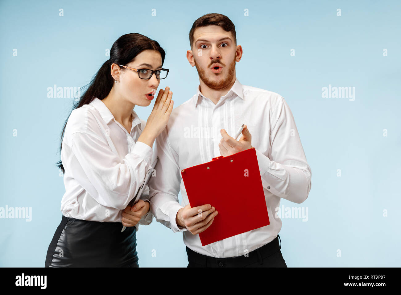 The surprised business man and woman smiling on a blue studio ...