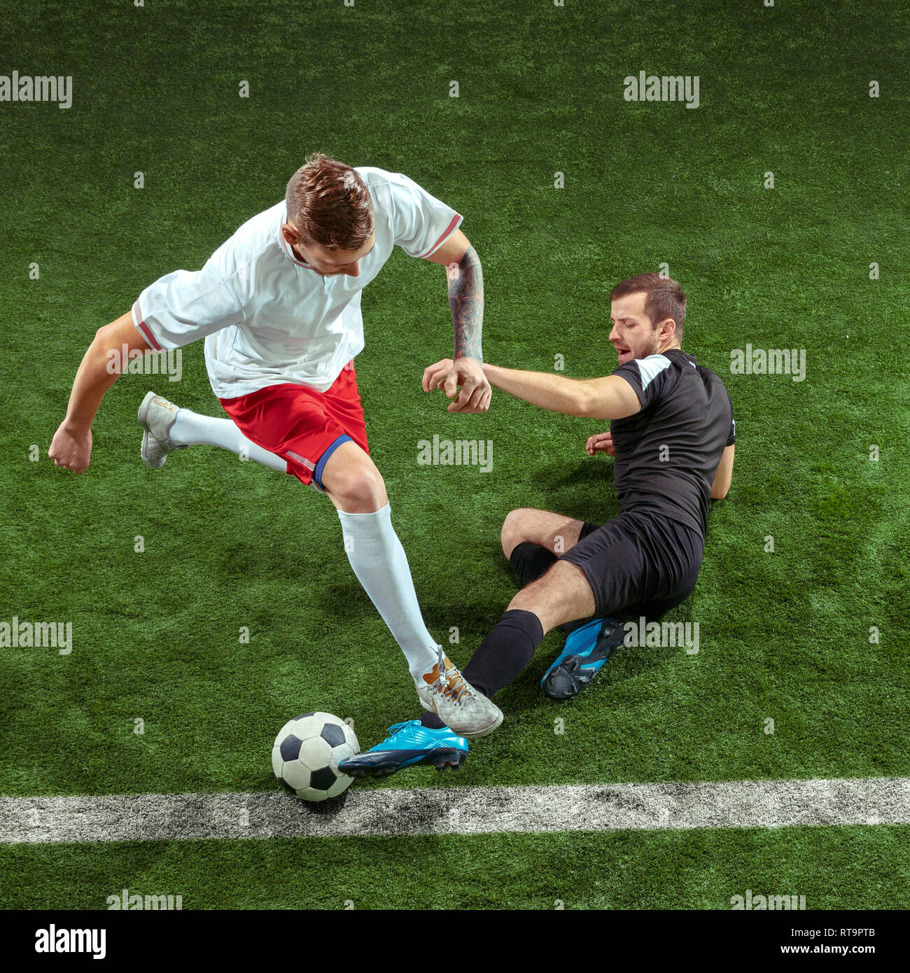 Football player tackling for ball over green grass background