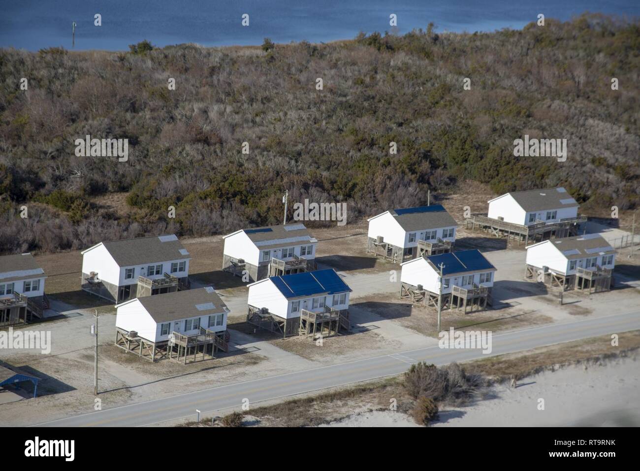 Blue tarps line the roofs of recreational lodging on the coast of