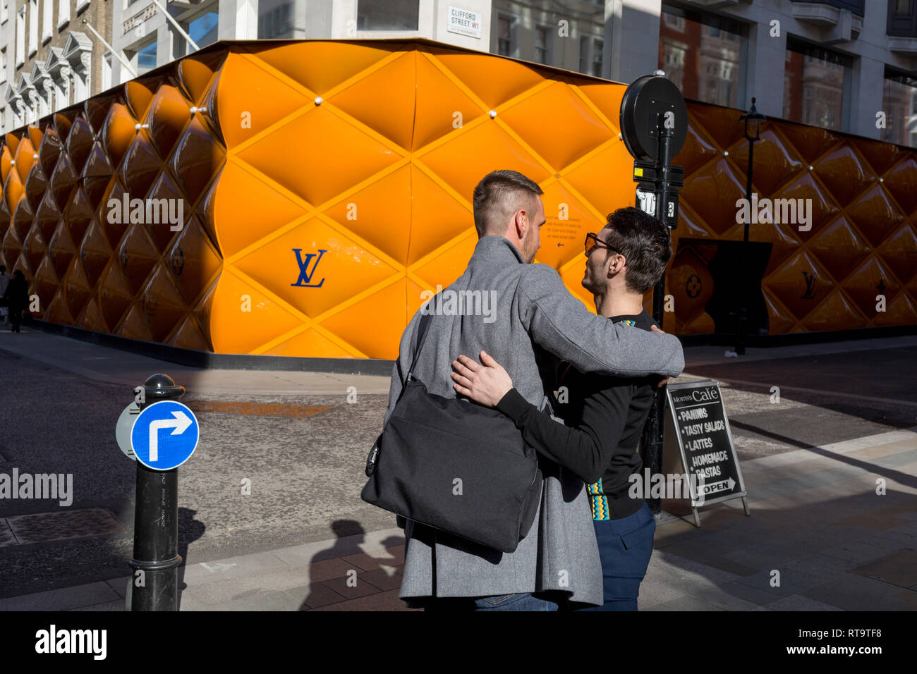 greet each other opposite the temporary renovation hoarding of luxury brand Louis in New Bond Street, 25th February 2019, in London, England Stock Photo -