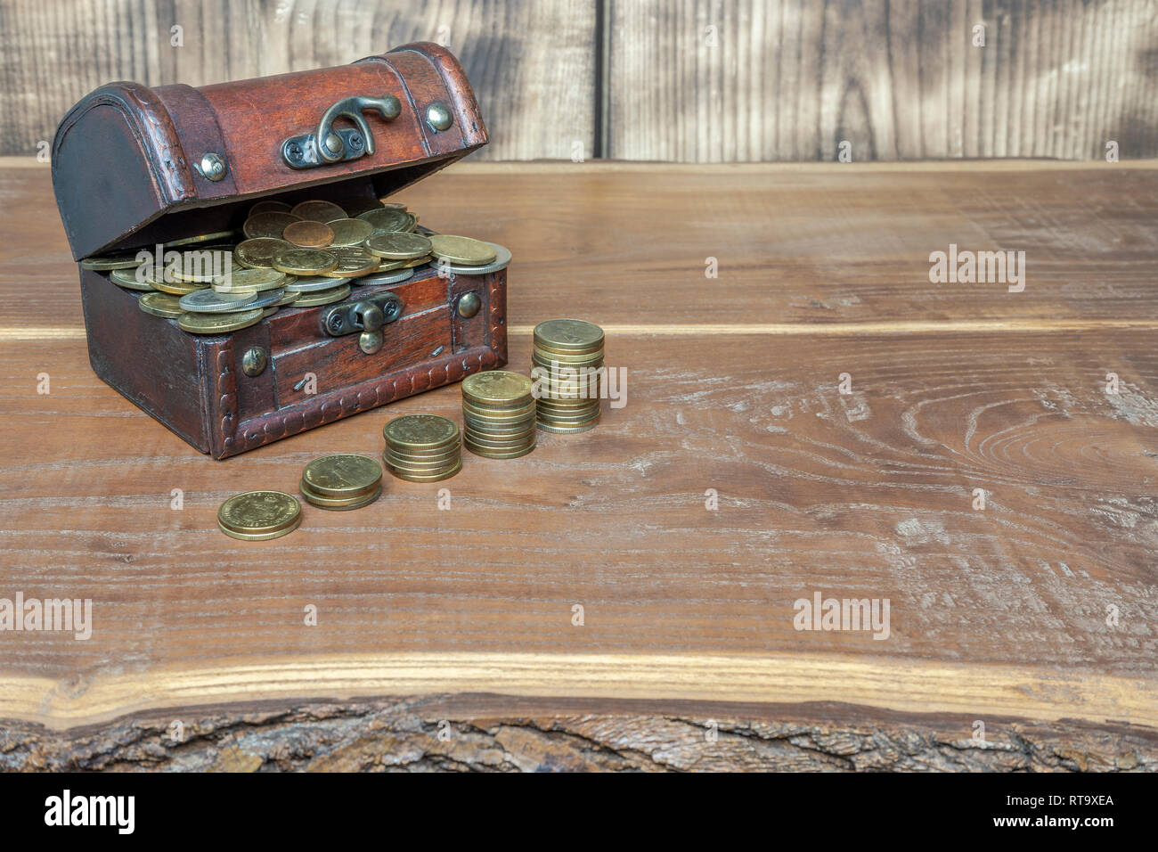 A retro suitcase filled with gold and silver coins, in front of them