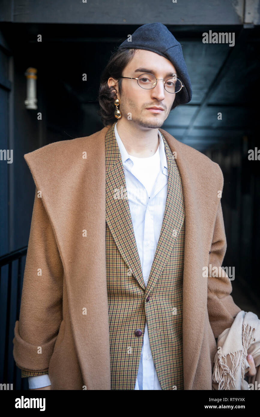 LONDON - FEBRUARY 15, 2019: Stylish attendees gathering outside 180 The Strand for London Fashion Week. A man in a brown coat, sandy tight pants and a Stock Photo