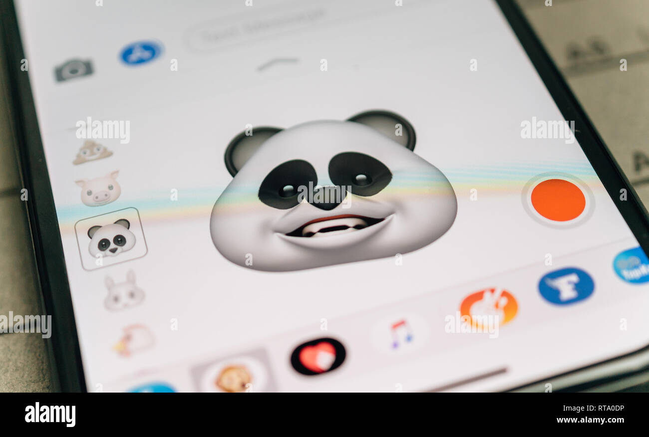 PARIS, FRANCE - NOV 9 2017: Panda bear 3d animoji emoji generated by Face ID facial recognition system with smiling face emotion close-up of the new iphone X 10 Display - tilt-shift lens used  Stock Photo
