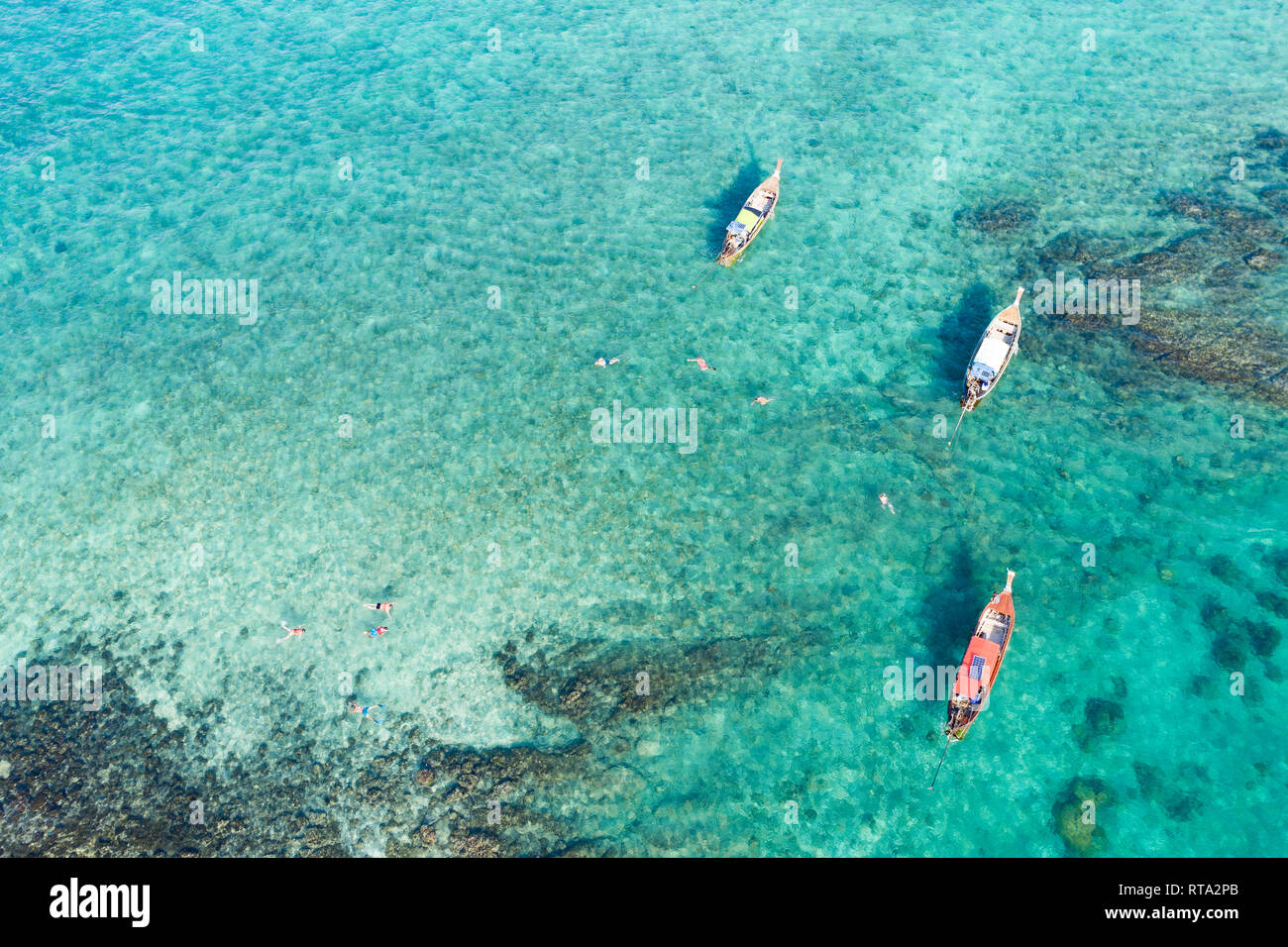 View from above, stunning aerial view of some long-tails boats and tourists who do snorkeling in a beautiful, transparent and turquoise sea. Stock Photo