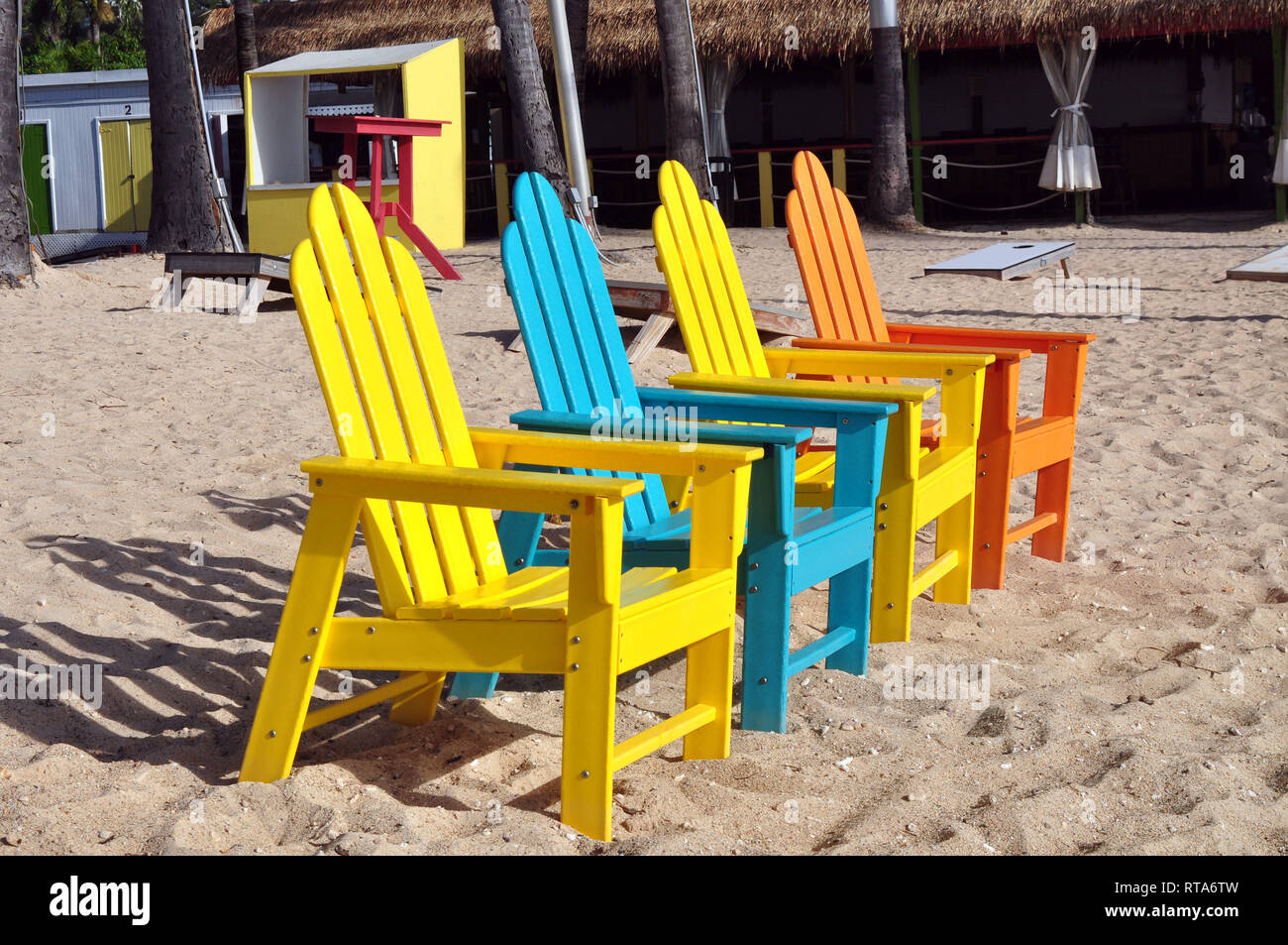 Four Bright Colored Adirondack Chairs In The Sand Stock Photo