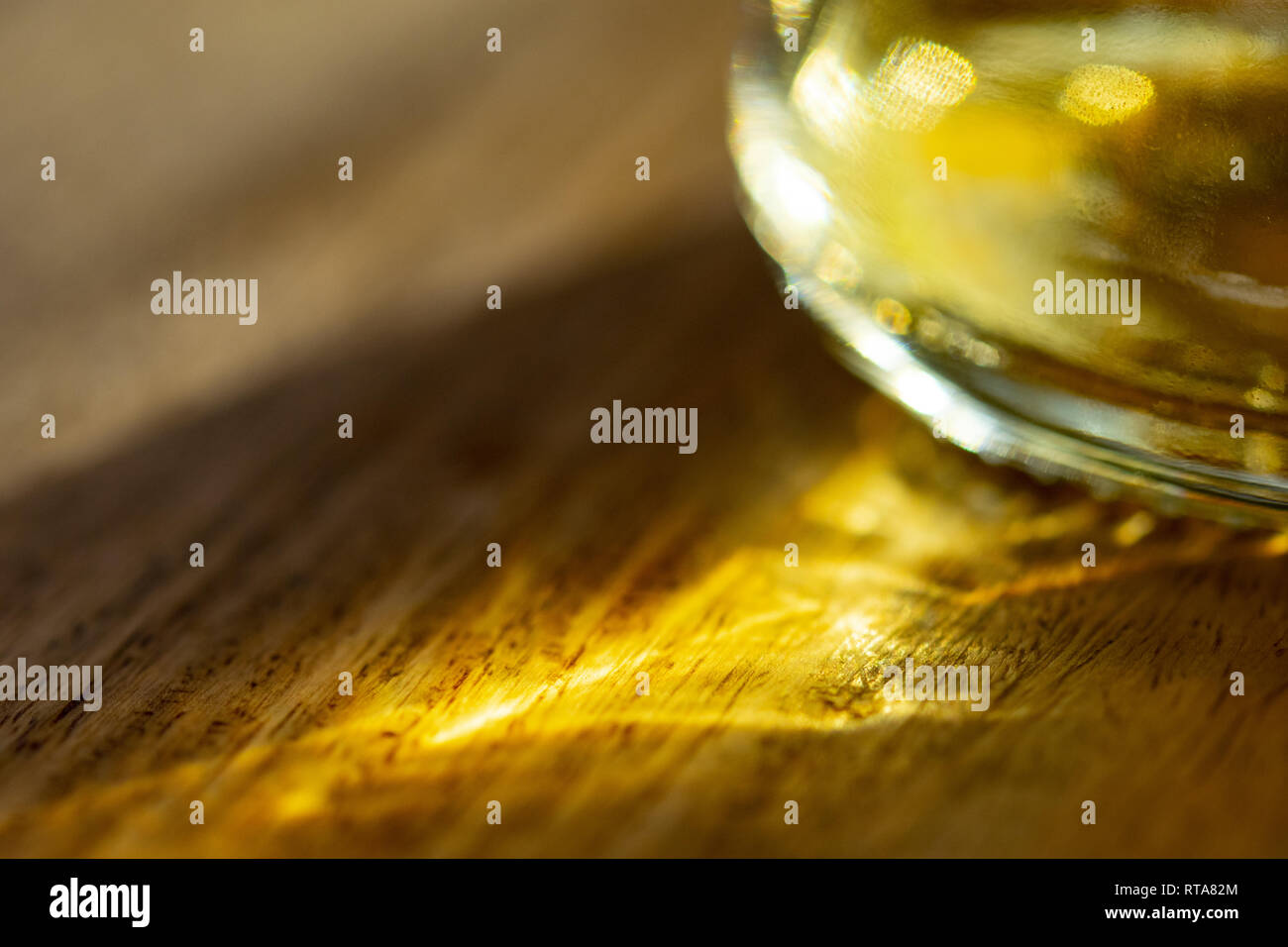 pattern solar through a glass bottle oil reflected on a wooden base Stock Photo