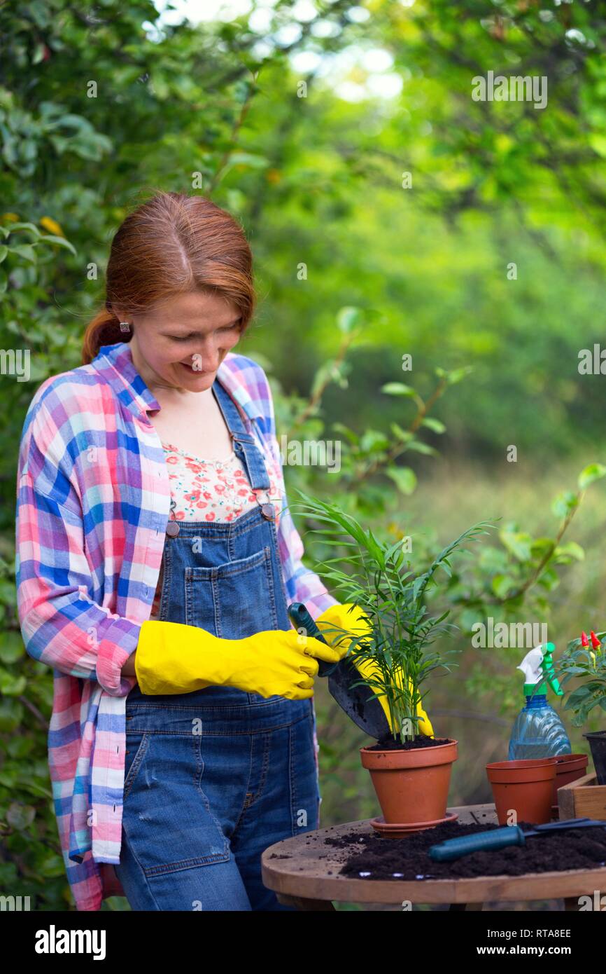 smiling girl plants a flowers in the garden. flower pots and plants for ...