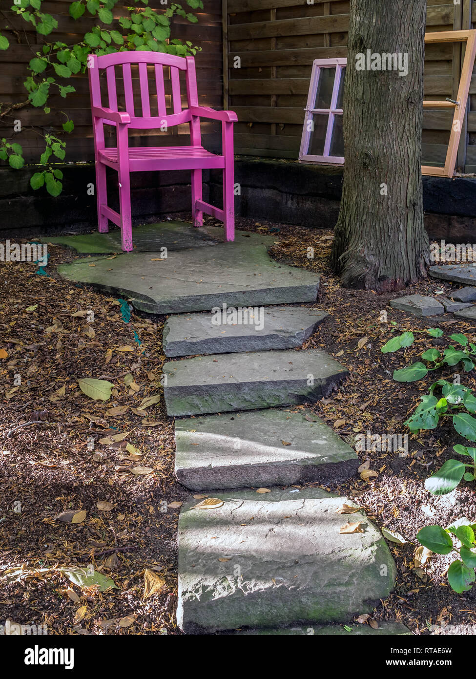 Snug place in the old garden with pink wooden chair Stock Photo