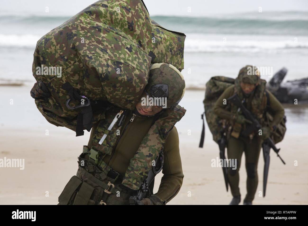 Japan Ground Self-Defense Force (JGSDF) Soldiers carry gear inland after performing a surf passage in combat rubber raiding crafts during Iron Fist 2019, Feb. 1, on U.S. Marine Corps Base Camp Pendleton, CA. Exercise Iron Fist is an annual, multilateral training exercise where U.S. and Japanese service members train together and share techniques, tactics and procedures to improve their combined operational capabilities. Stock Photo