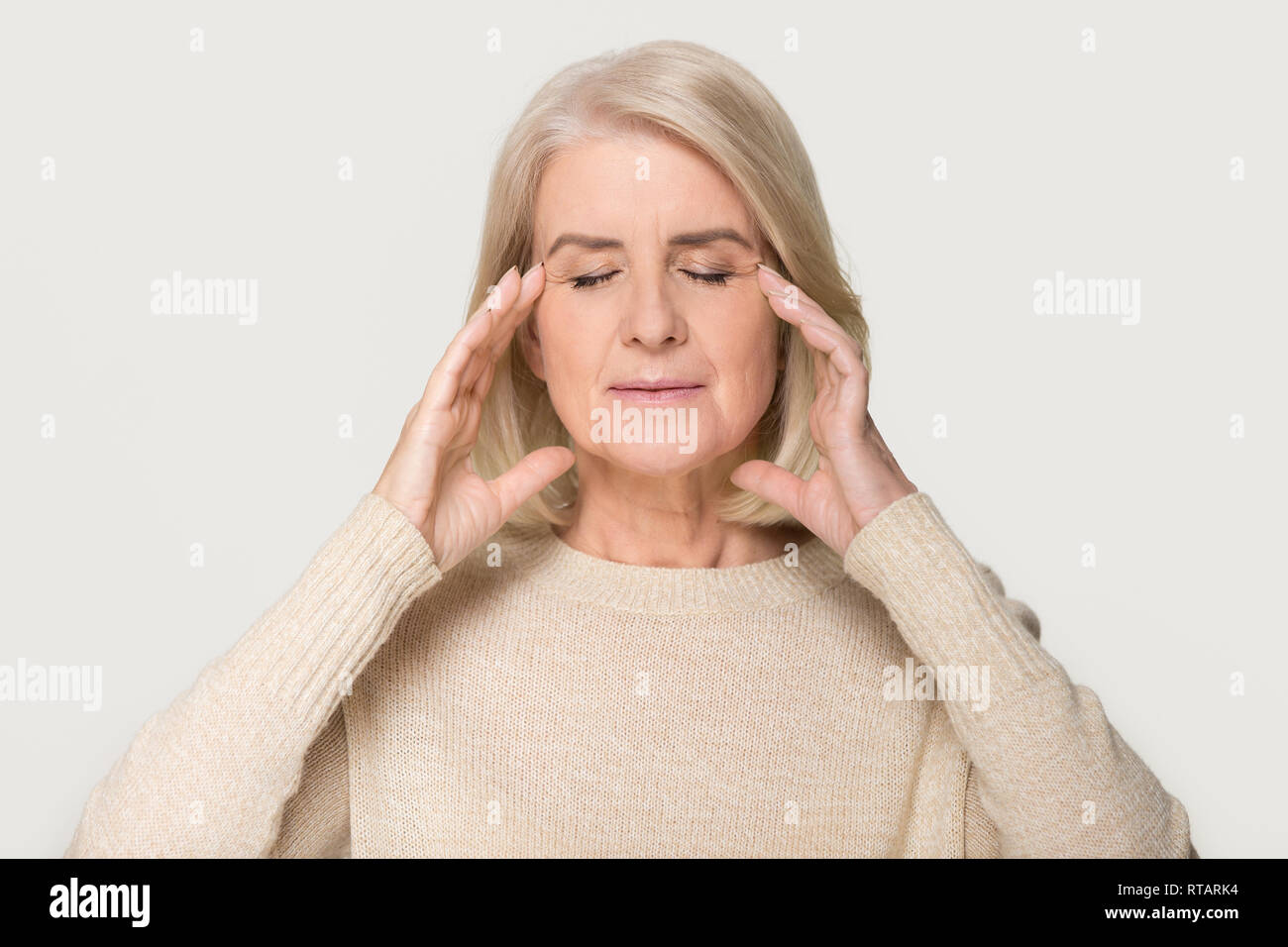 Calm healthy old woman massaging temples feeling stress relief Stock Photo