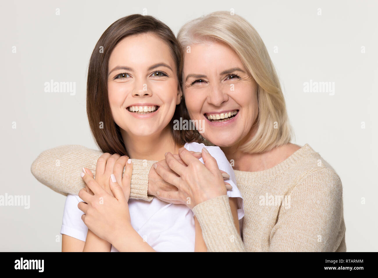 Happy old mother embracing young daughter isolated on background Stock Photo