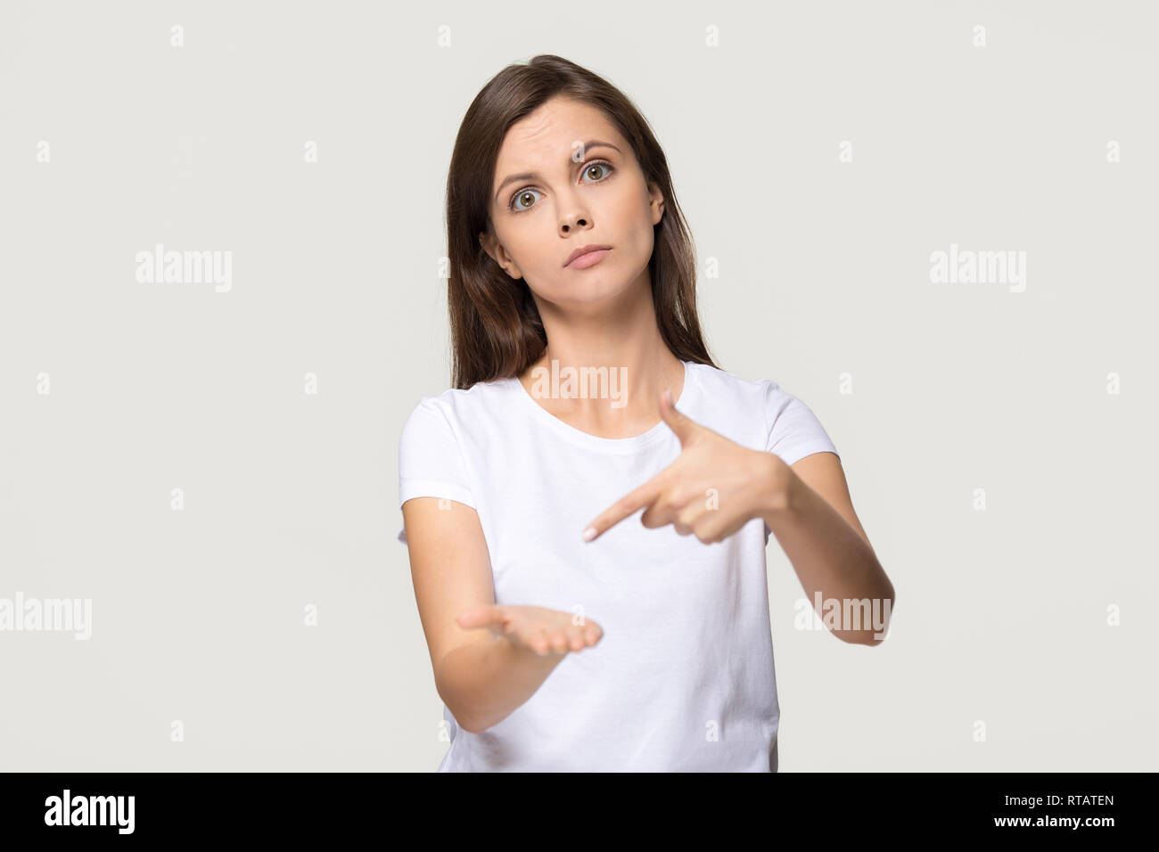 Annoyed girl pointing at copy space isolated on grey background Stock Photo