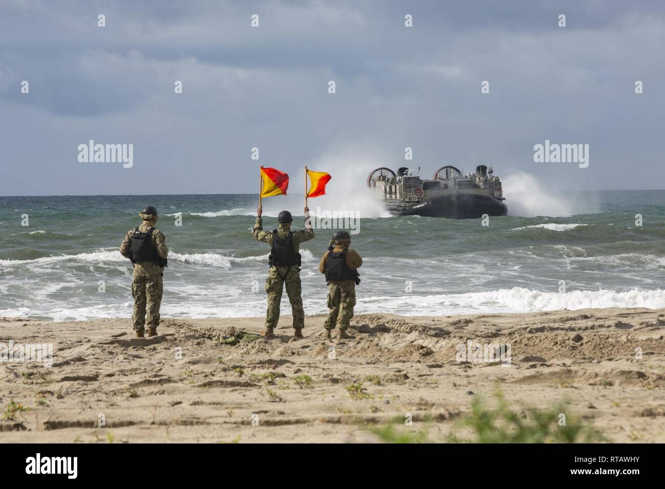 U.S. Sailors give the go ahead for a landing aircraft, air cushion to come ashore so Japan Ground Self-Defense Force (JGSDF) Soldiers with 1st Amphibious Rapid Deployment Regiment, can off load vehicles during an amphibious landing exercise for Iron Fist 2019, Feb. 4, on U.S. Marine Corps Base Camp Pendleton, CA. Exercise Iron Fist is an annual, multilateral training exercise where U.S. and Japanese service members train together and share techniques, tactics and procedures to improve their combined operational capabilities. Stock Photo