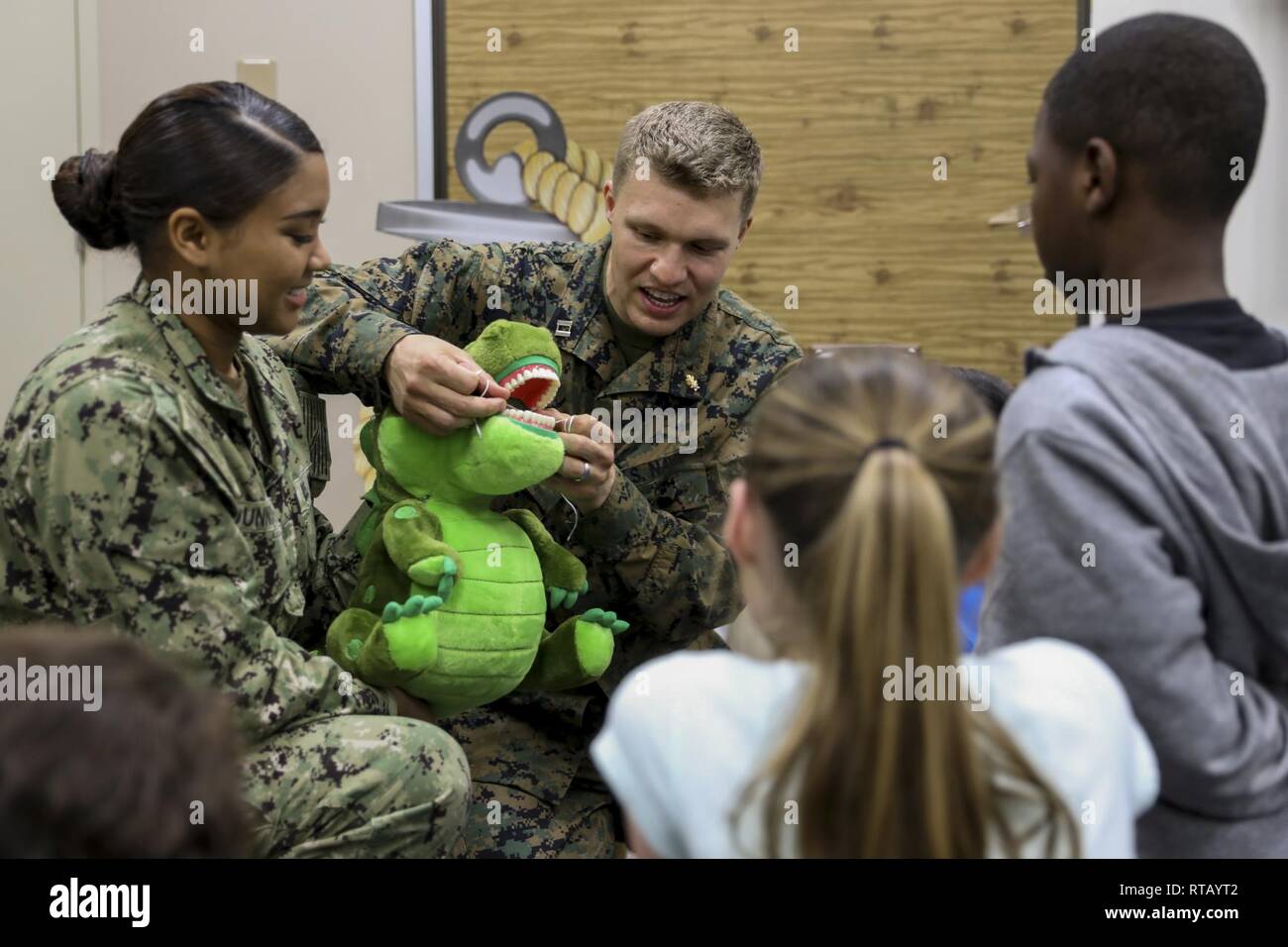 Navy Lt. Michael J. Lawrence, center left, and Seaman Lauryn A. Dunning, left, demonstrate how to properly floss teeth to students from Kinser Elementary School Feb. 5, 2019 on Camp Kinser, Okinawa, Japan. Sailors from Naval clinics in Okinawa held a presentation to promote oral health awareness during National Children’s Dental Health Month. Lawrence, a general dentist with Branch Dental Clinic Evans, 3rd Dental Battalion, 3rd Marine Logistics Group, is a native of Troutdale, Oregon. Dunning, a hospital corpsman with Branch Dental Clinic Futenma, 3rd Dental Bn., 3rd MLG, is native of New Orle Stock Photo
