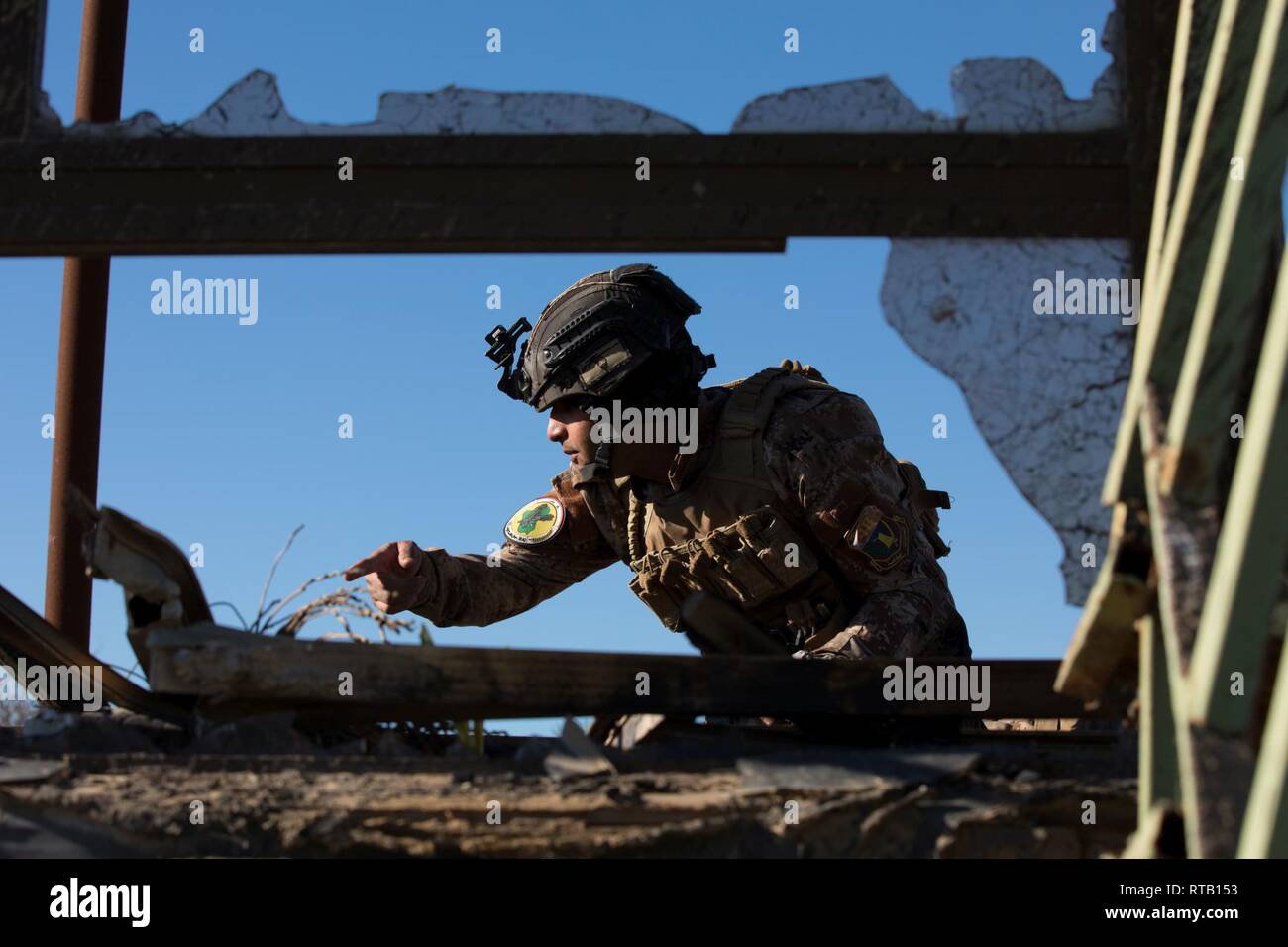 An Iraqi Counter-Terrorism Service Basic Leader Course student communicates with his team as they conduct a tactical movement to clear a training objective near Baghdad, Iraq, Feb. 5, 2019. BLC teaches junior leaders the skills and actions needed to develop their individual leadership abilities.  Coalition forces advise and assist the Iraqi instructors in a united effort to build an elite, self-sustaining force that can secure Iraq’s sovereign borders, protect the population and ensure the lasting defeat of ISIS. Stock Photo