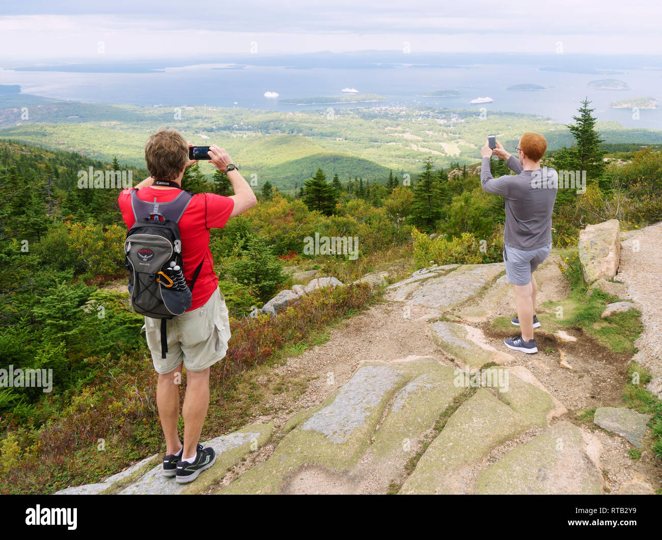 Visitors taking pictures of Frenchman Bay with their cellphones from the top of Cadillac Mountain in Acadia National Park, Maine, USA. Stock Photo